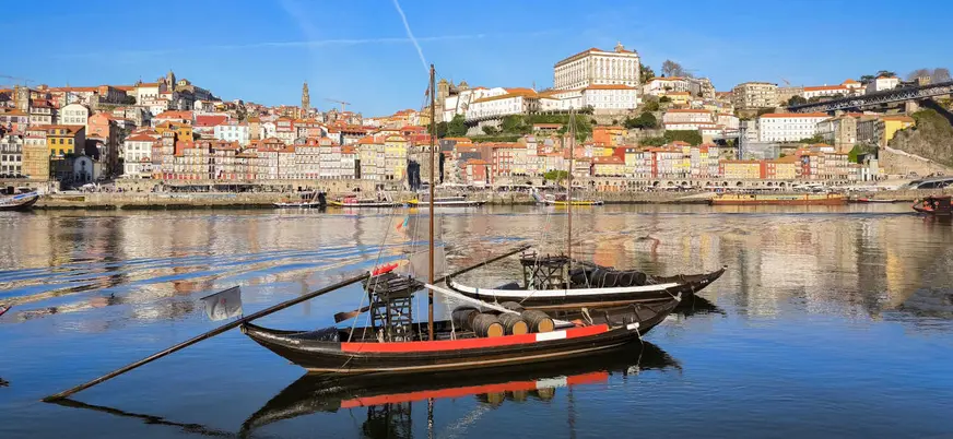 Barcos rabelos con barricas en el Duero frente a las casas de la Ribeira de Oporto