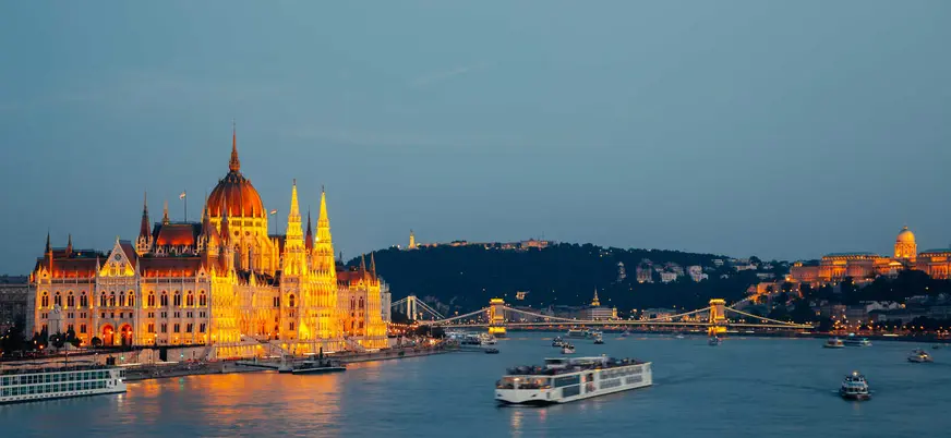 El Parlamento de Budapest iluminado de noche, visto desde un crucero en el Danubio.