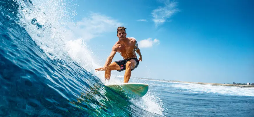 Surfista manteniendo el equilibrio en la ola, clases de surf en Llanes