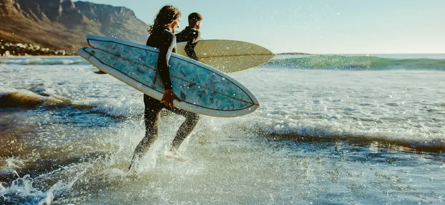 Surfistas entrando al mar en la playa de San Antolín, Llanes, Asturias