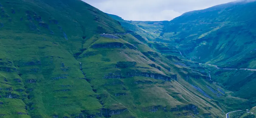 Carretera entre montañas verdes en los Valles Pasiegos de Cantabria.