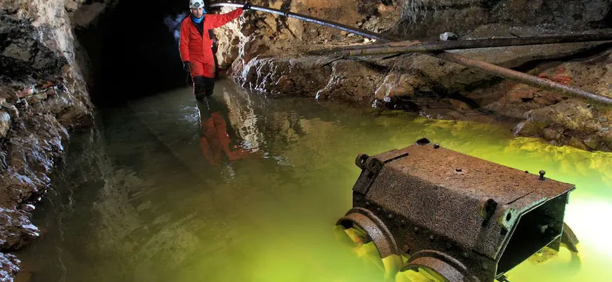 Exploración en la mina de El Soplao, Cantabria, con agua iluminada en la galería.