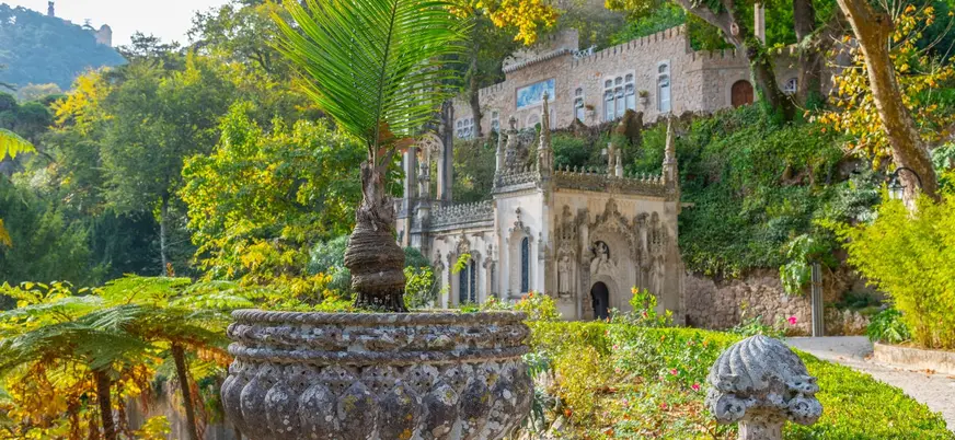 Jardines y fachada decorada de Quinta da Regaleira en un entorno verde de Sintra