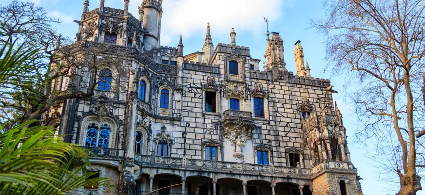 Fachada principal del palacio de Quinta da Regaleira entre árboles en Sintra