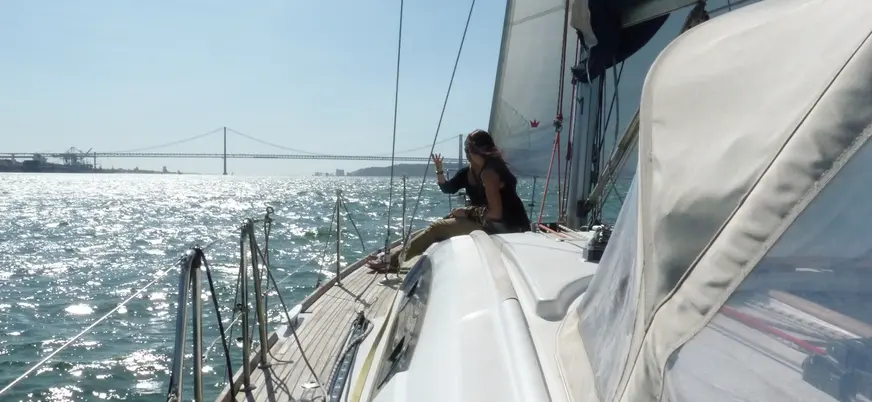 Persona disfrutando de un paseo en velero por el Tajo con el puente al fondo.