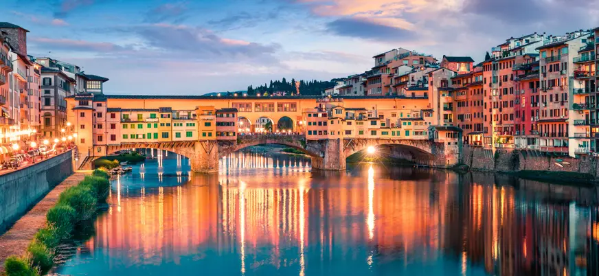 Ponte Vecchio iluminado al anochecer sobre el río Arno en Florencia