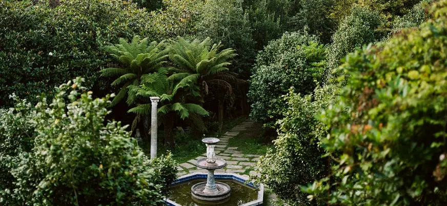 Fuente histórica entre la vegetación del jardín de Fonte Baxa, Luarca, Asturias