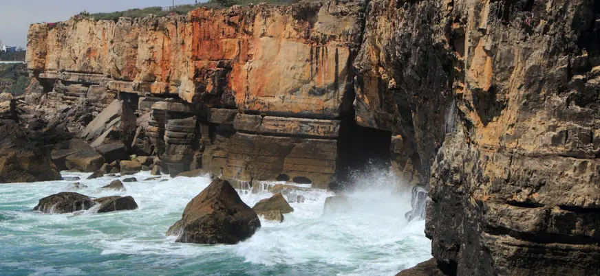 Acantilados de Cascais con olas rompiendo en la cueva de la Boca do Inferno.