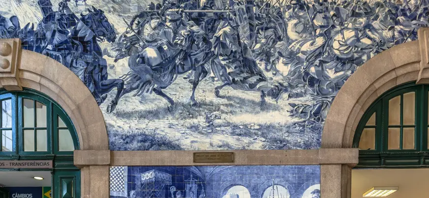 Paneles de azulejos azules en São Bento con escenas históricas de batallas medievales.