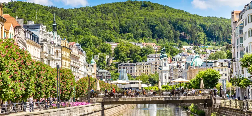 Río Teplá fluye entre edificios balneario y frondosas colinas en Karlovy Vary.