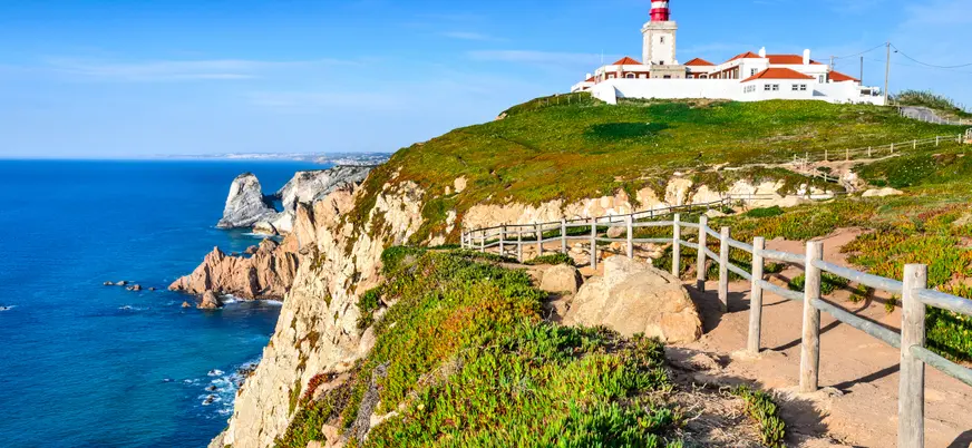 Acantilados y faro de Cabo da Roca con sendero junto al océano Atlántico.