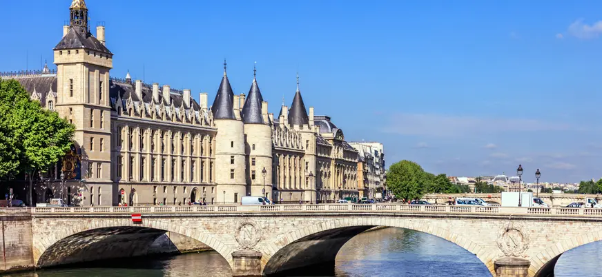 La Conciergerie y el puente sobre el río Sena en París, con arquitectura gótica y cielo despejado."