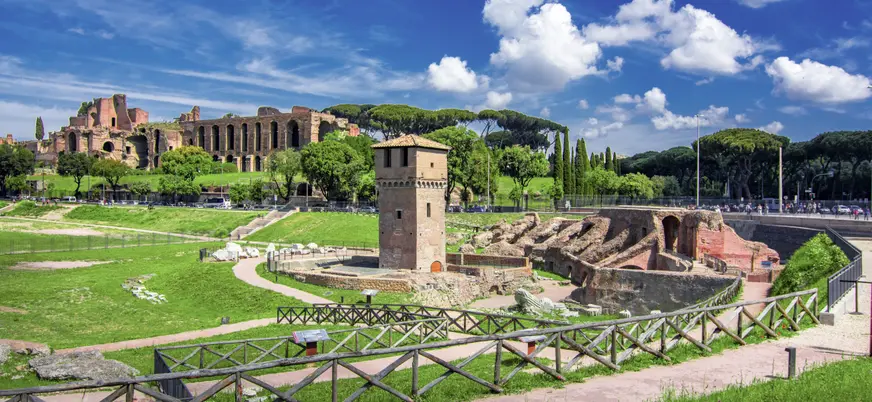 Ruinas de las Termas de Caracalla en Roma, con altos muros de ladrillo, arcos monumentales y áreas verdes bajo cielo despejado.