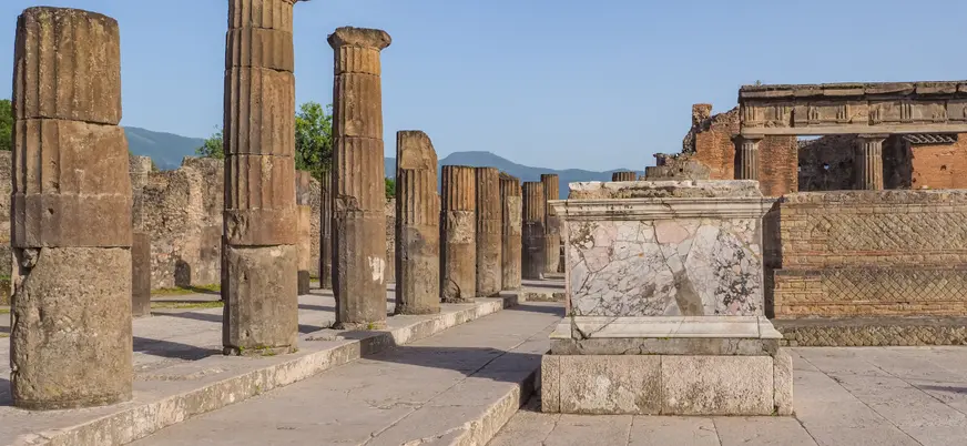 Ruinas clásicas con columnas de piedra y altar de mármol bajo cielo despejado.