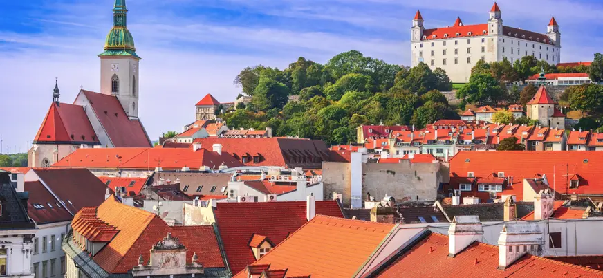 Vista panorámica de Bratislava con tejados rojos, la Catedral de San Martín a la izquierda y el Castillo de Bratislava en lo alto de una colina al fondo.