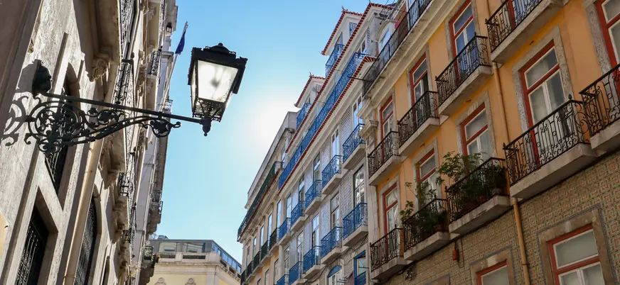 Calle del centro de Lisboa con fachadas de azulejos y balcones de hierro forjado.
