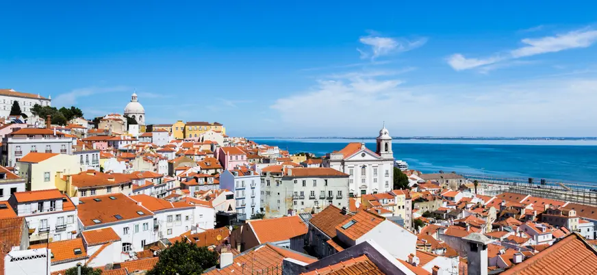 Panorámica del mirador de Santa Lucía con Alfama y el río Tajo bajo un cielo despejado.