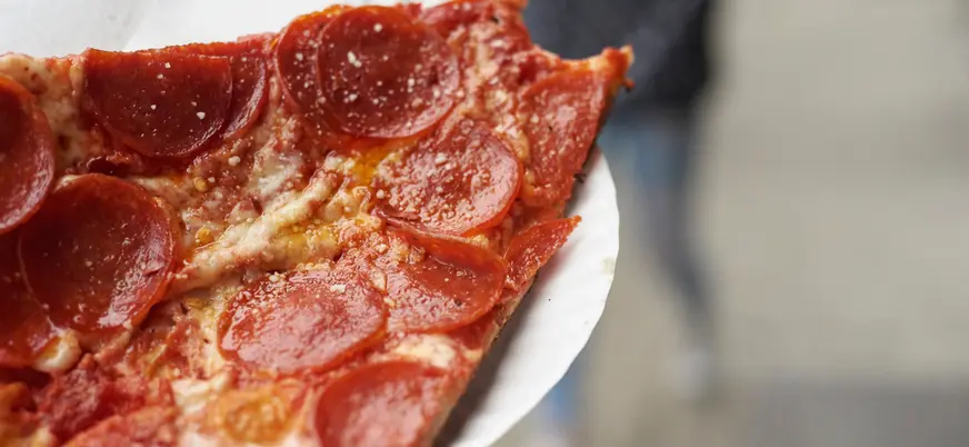 **Alt sugerido (≤80 caracteres):** Porción de pizza en un free tour gastronómico por Greenwich Village, Nueva York