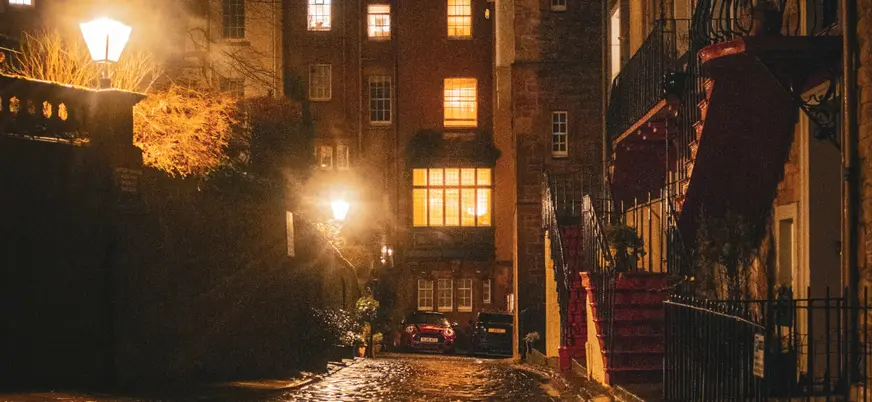 Calle adoquinada en el casco antiguo de Edimburgo, iluminada por farolas