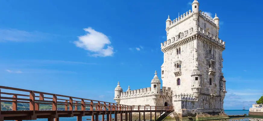 Torre de Belém reflejada en el agua bajo un cielo azul en Lisboa