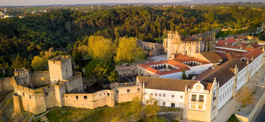 Vista aérea del Convento de Cristo y su muralla medieval rodeados de bosque en Tomar.