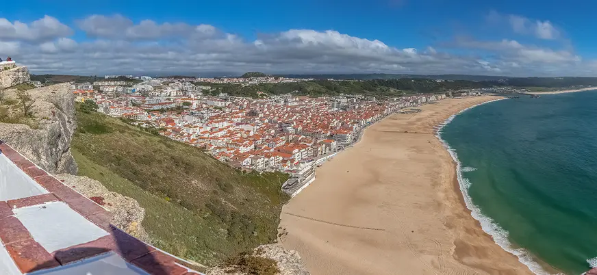 Vista panorámica de Nazaré con su extensa playa, el mar y las casas de tejados rojos.
