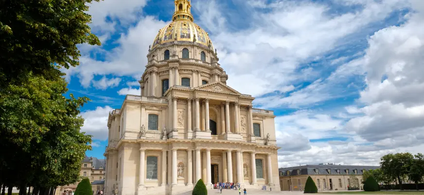 Hôtel des Invalides en París con cúpula dorada y cielo azul con nubes.