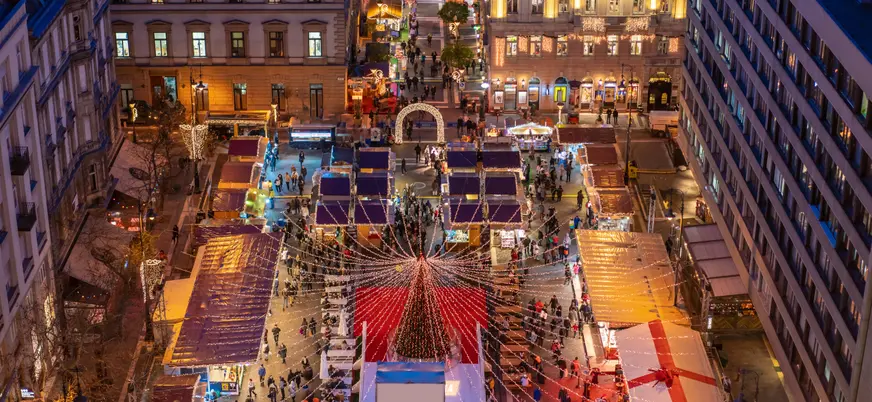 Vista aérea de un concurrido mercado navideño en Budapest al atardecer.