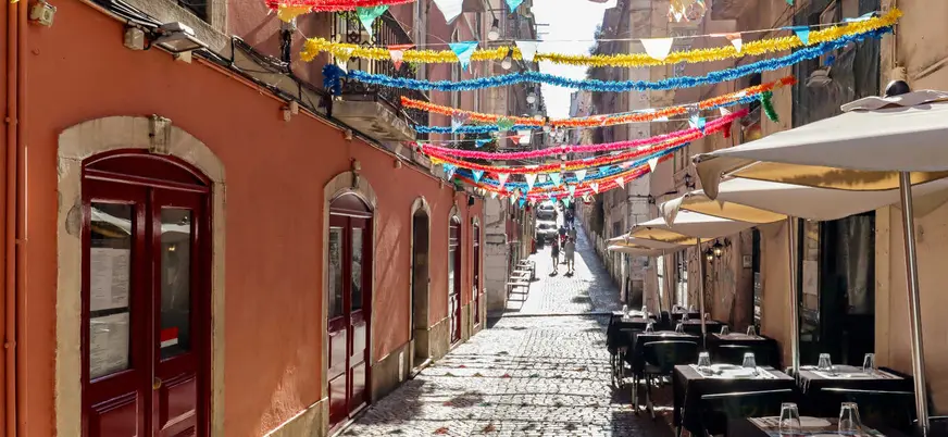 Calle decorada en la Mouraria de Lisboa con guirnaldas y terrazas