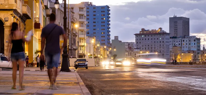 Pareja caminando al atardecer por La Habana, en una ruta de bares y baile