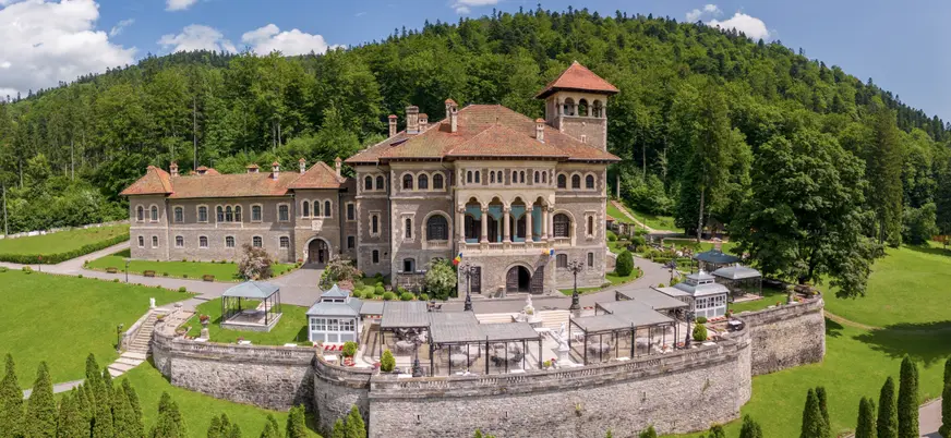 Panorámica del Castillo de Cantacuzino y su entorno, con vegetación y montañas alrededor del edificio.