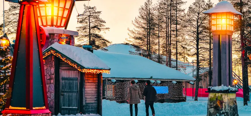Pareja paseando por el pueblo de Papá Noel al atardecer.