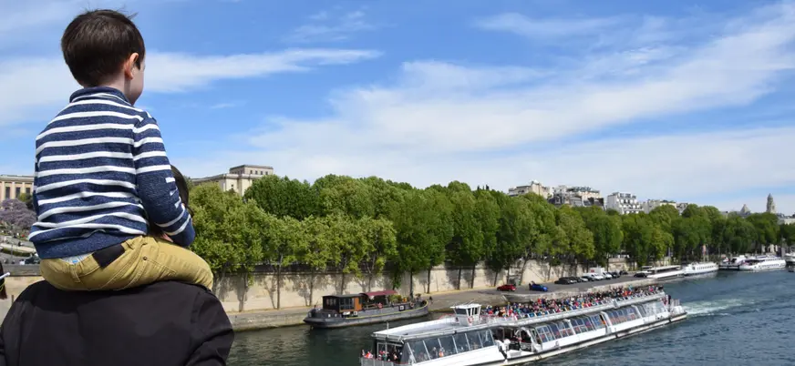 Familia observando un bateau mouche, uno de los barcos más famosos de París que navegan el río Sena.