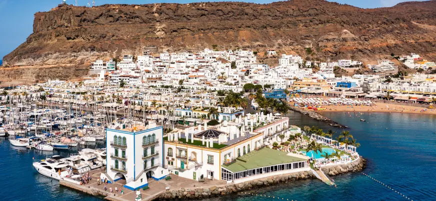 Vista aérea de Puerto de Mogán, donde se ve la playa, la localidad al completo y las montañas de los alrededores.