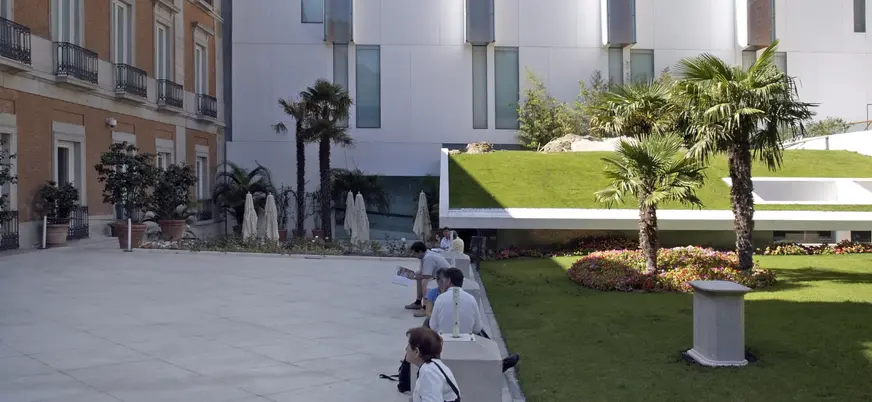 Edificio del Museo Thyssen con gente descansando en bancos.