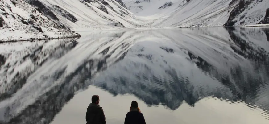 Pareja con las montañas de los Andes reflejadas en la Laguna del Inca en la excursión desde Santiago de Chile.