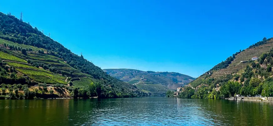 Vista del río Duero entre colinas con terrazas de viñedos bajo un cielo despejado.