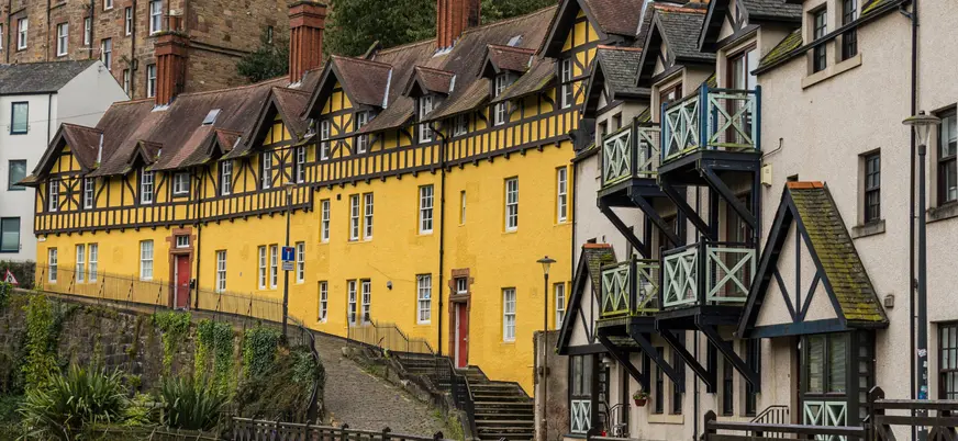 Vista de la arquitectura típica de Dean Village, con sus casas de piedra de estilo escocés y tejados a dos aguas, rodeadas de naturaleza.