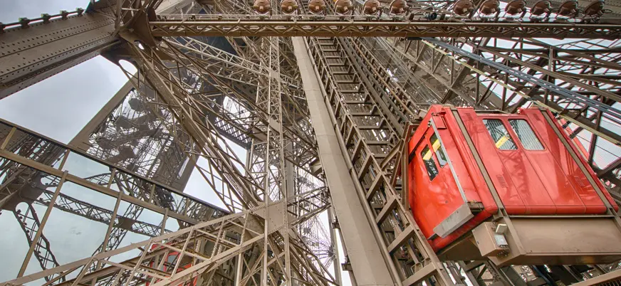 Ascensor rojo subiendo por la estructura de hierro de la Torre Eiffel en París