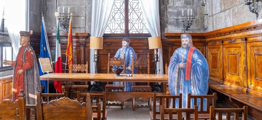 Caballeros de la Noche observando desde la sombra en una sala de juicio, presentes como figuras de autoridad en un tribunal medieval.