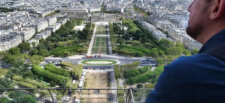 Hombre observando el Campo de Marte desde la Torre Eiffel en París
