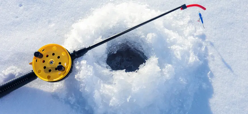 Primer plano de un agujero de hielo y caña de pescar en Rovaniemi, listo para una captura en el invierno ártico.