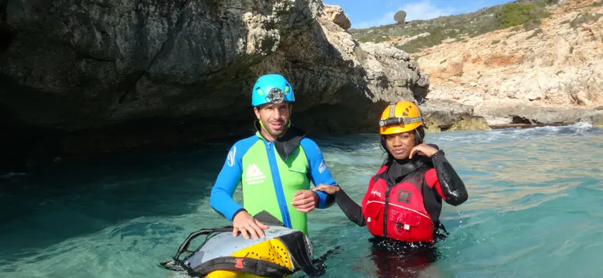 Aventureros con el traje de neopreno y el casco, incluidos en esta actividad de espeleología.