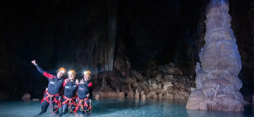 Dentro de la Cova de Coloms, los visitantes capturan la belleza de las formaciones rocosas.
