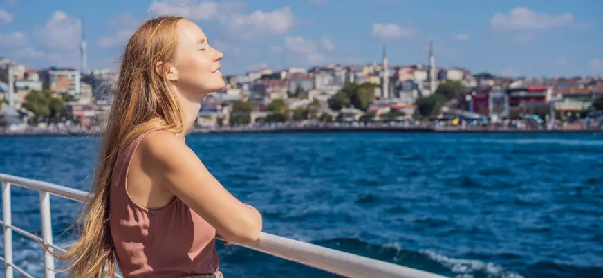 Mujer disfrutando del sol en barco por el Bósforo, Estambul, Turquía