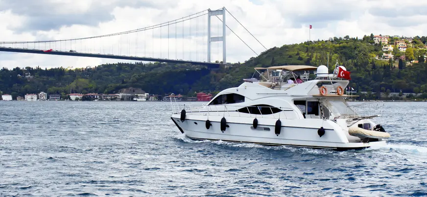 Yate de lujo navegando bajo un puente del Bósforo en Estambul, Turquía