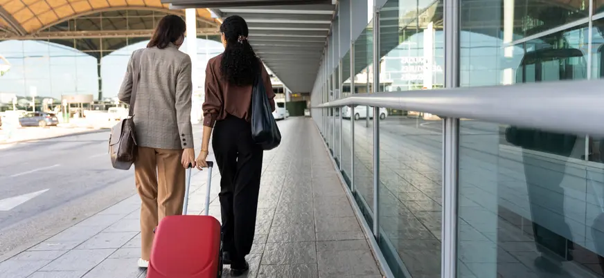 Dos chicas se bajan del avión con su maleta, para encontrarse con el personal de su traslado.