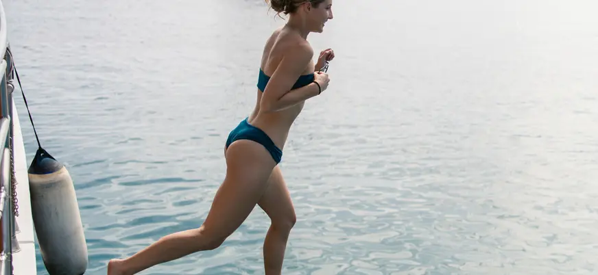 Chica saltando en el agua para darse un chapuzón en aguas tranquilas antes de la cena. 