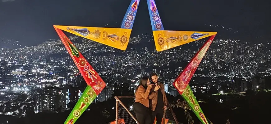 Pareja se realiza una fotografía en uno de los miradores de Medellín con un marco de colores.