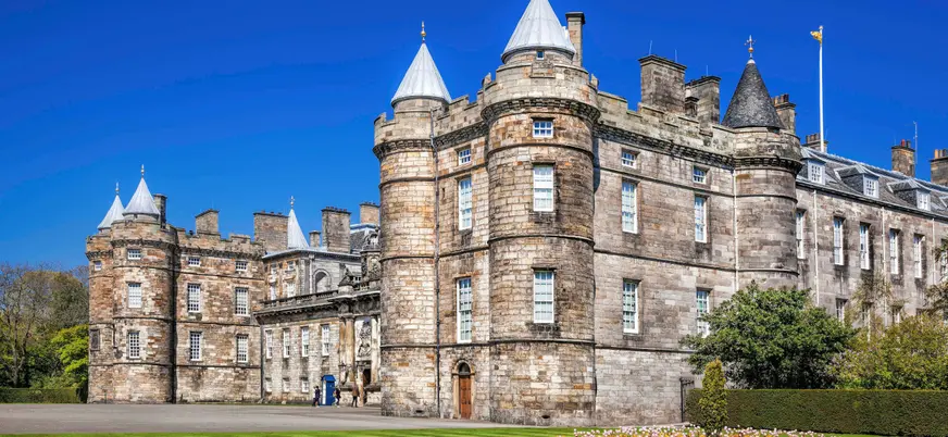 Fachada principal del Palacio de Holyroodhouse en Edimburgo bajo un cielo azul despejado
